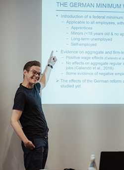 The picture shows a participant of the GradAB closed meeting 2019 holding a presentation.