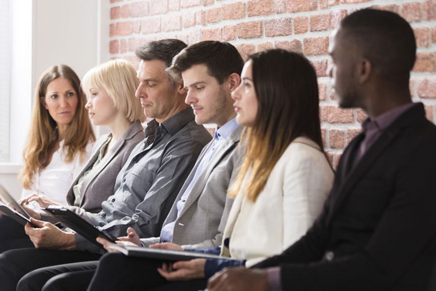 Three woman and three men are sitting and waiting in an row