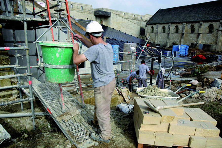 Drei Bauarbeiter arbeiten auf einer Baustelle.