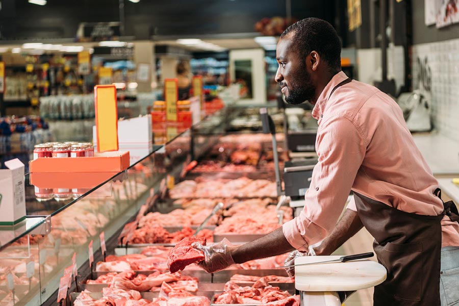 A butcher shop salesman works at the counter.