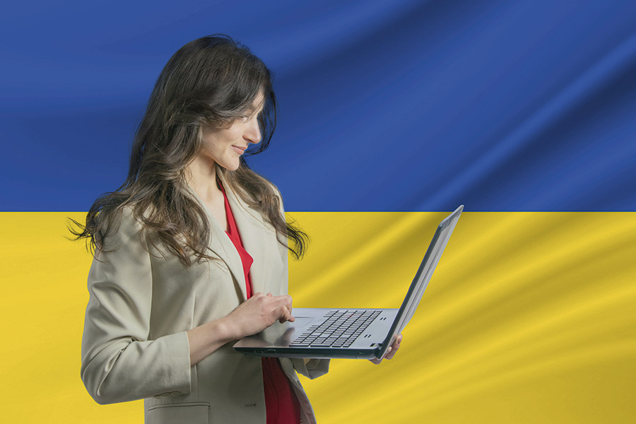 Junge Frau verwendet Laptop vor dem Hintergrund der Flagge der Ukraine