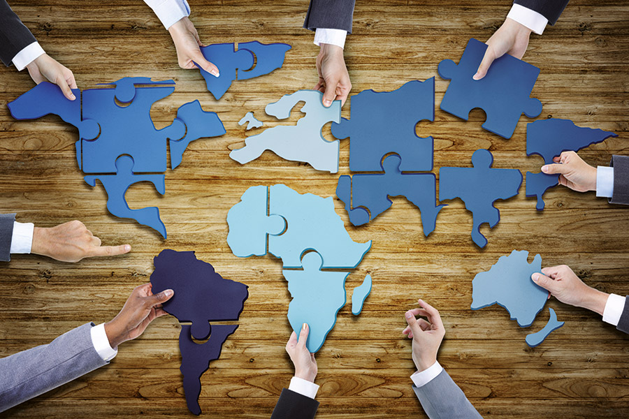 Geschäftsleute halten Puzzleteile der Weltkarte in den Händen