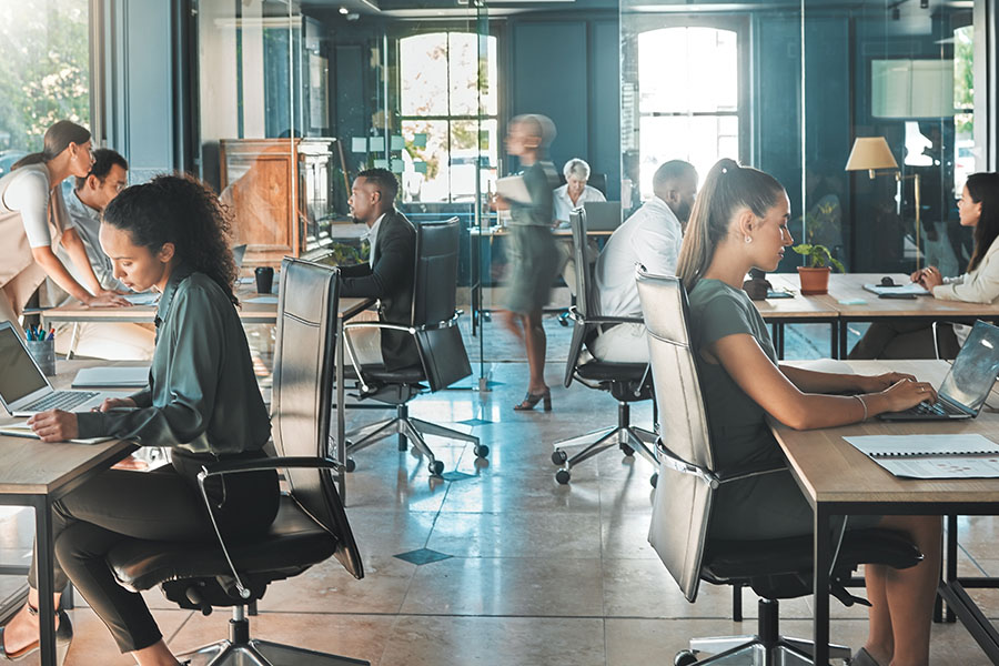 Männer und Frauen arbeiten in einem modernen Großraumbüro.