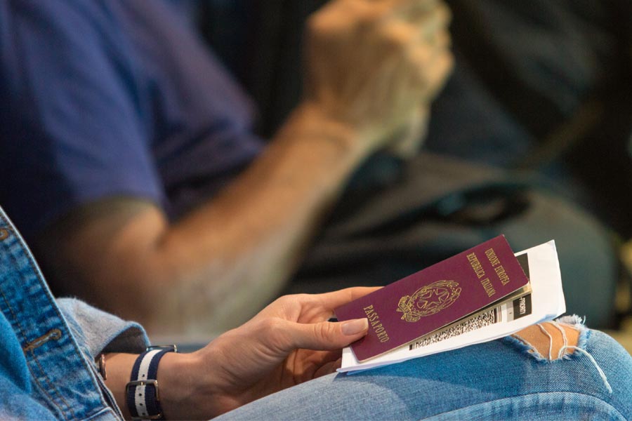 Woman waiting for her flight in the airport lobby with an Italian passport and boarding pass in her hand.