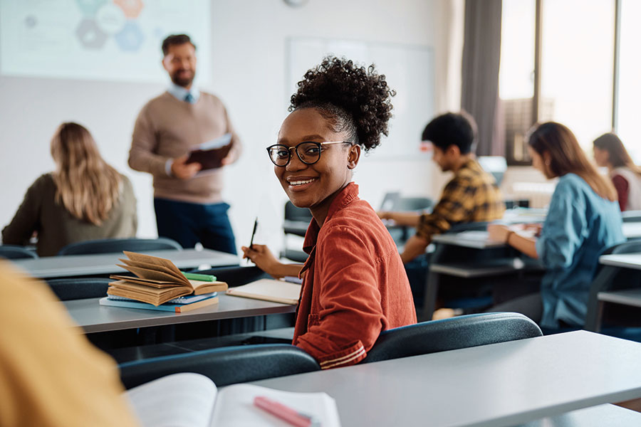 Young black woman turns around in classroom and smiles.