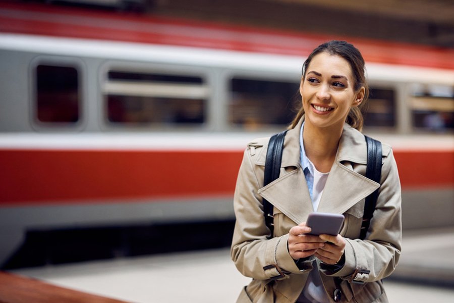 : Junge Frau mit Mobiltelefon vor einem stehende Zug.