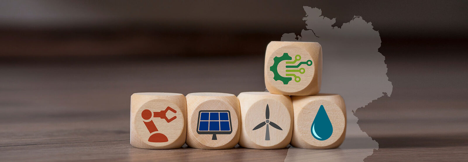 Five wooden cubes with symbols for digitalization and renewable energies lie on a wooden table.