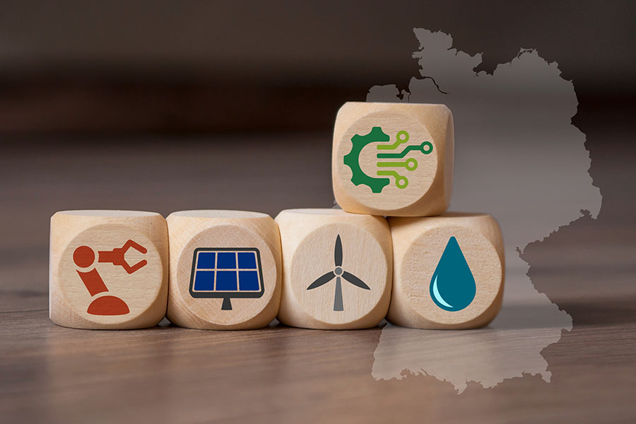 Fünf Holzwürfel mit Symbolen für Digitalisierung und erneuerbare Energien liegen auf einem Holztisch.