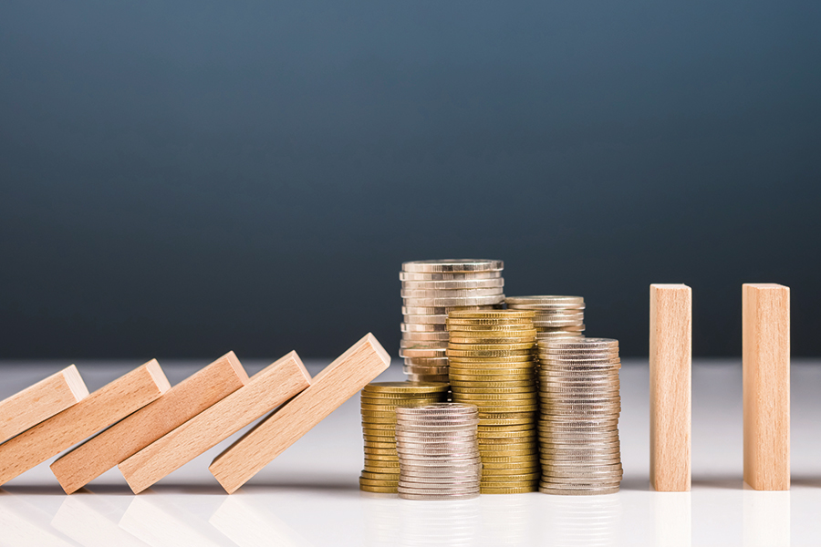 The picture shows a row of falling dominoes that are stopped by some stacks of coins.