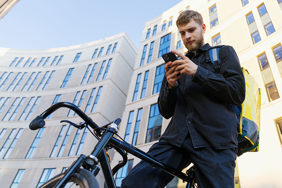 A male bicycle courier checks the new order in the app on his mobile phone.