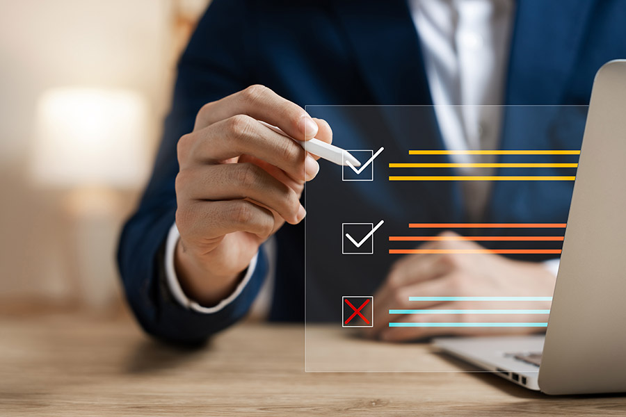 Geschäftsmann hakt mit einem Stift verschiedene Checkboxen in einen virtuellen, vor ihm schwebenden Fragebogen ab.