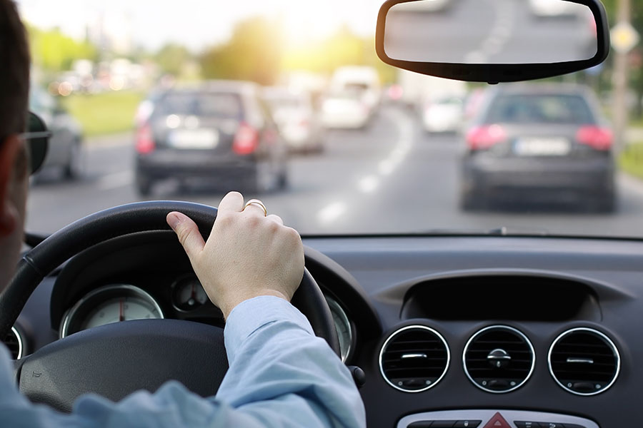 Aufnahme über die Schulter eines Autofahrers, der im Berufsverkehr fährt.