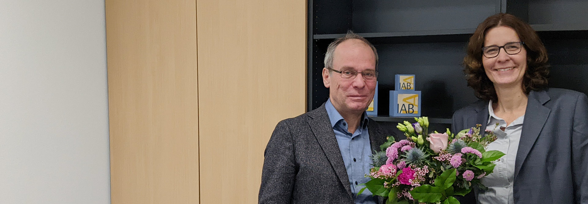 IAB-Direktor Bernd Fitzenberger begrüßt die neue IAB-Vizedirektorin Melanie Arntz mit einem Blumenstrauß.