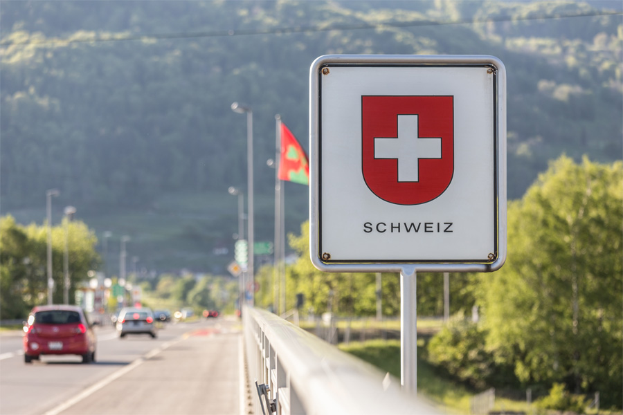 Autos fahren auf einer Straße über die Schweizer Grenze.