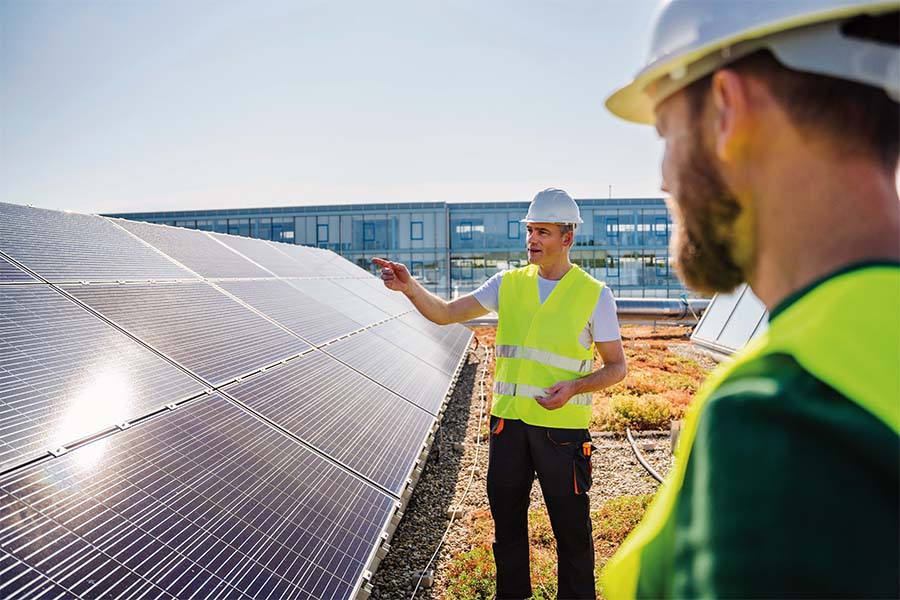 Zwei Techniker auf einem Dach vor einem Solarmodul.