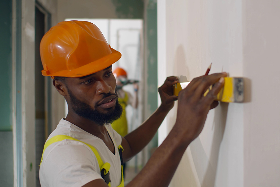 An African worker uses a spirit level to check whether a wall in a new building is straight.