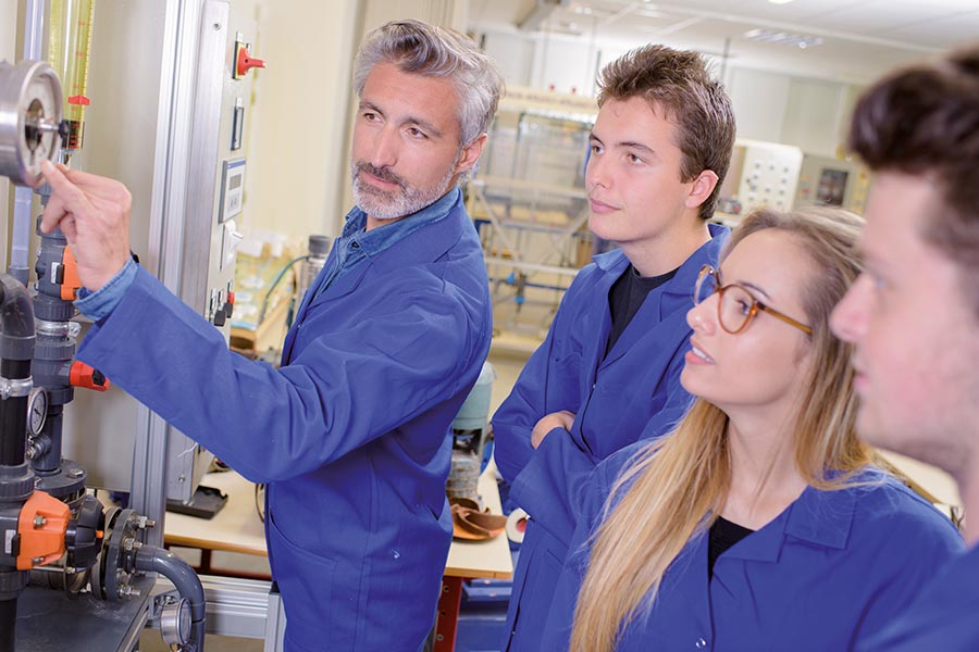 Ausbilder zeigt seinen Azubis eine Maschine
