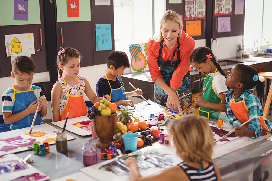 Teacher assisting schoolkids in drawing class
