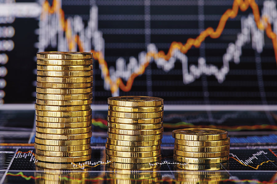 Abwärtstrend Stapel von Goldmünzen vor Finanzdiagramm