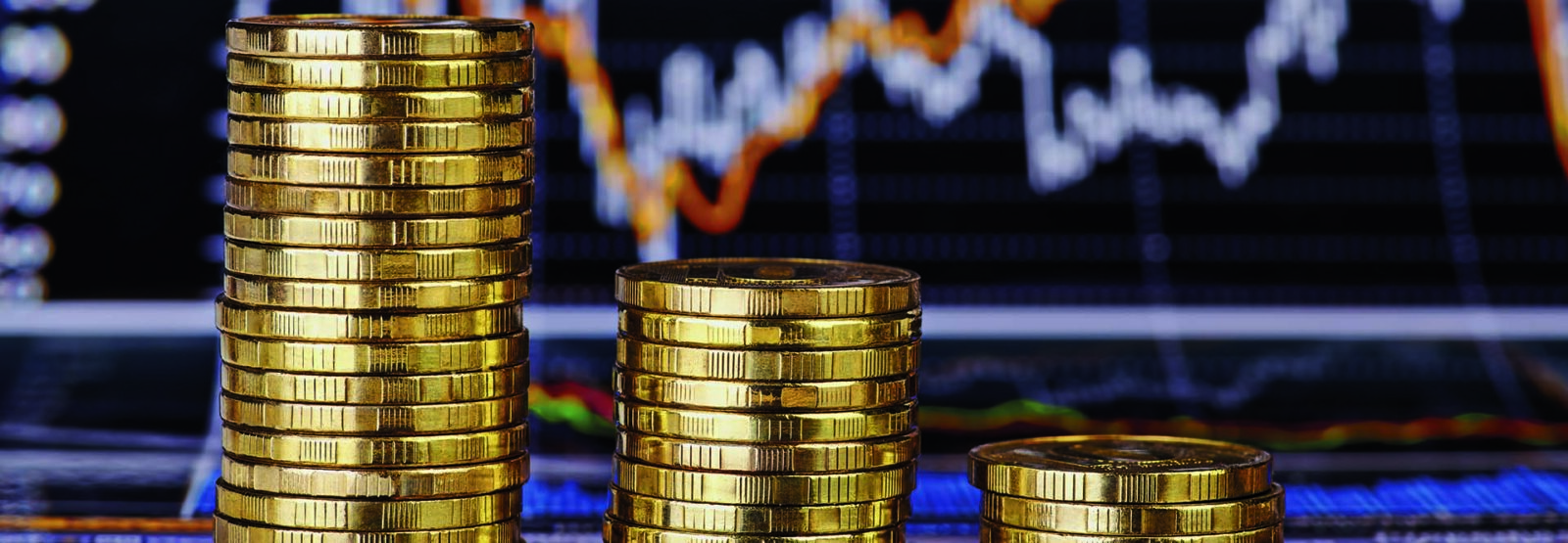 Abwärtstrend Stapel von Goldmünzen vor Finanzdiagramm