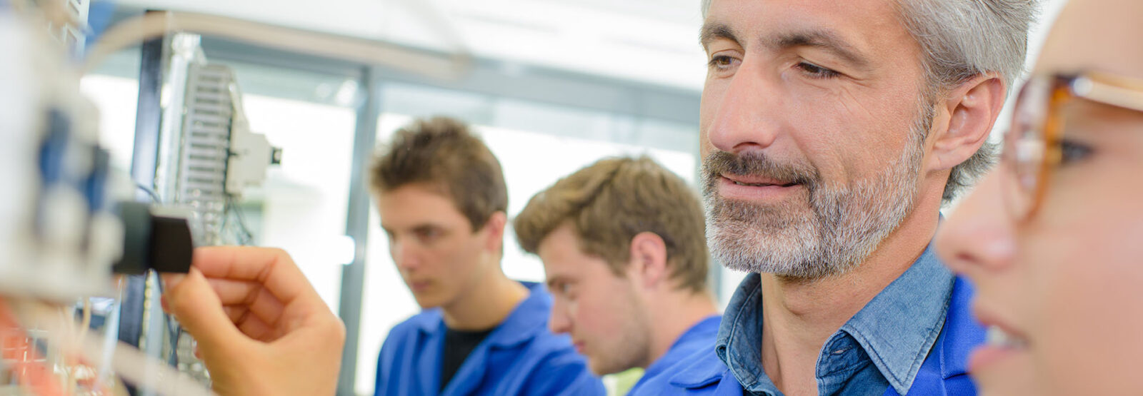 Lehrlinge und Meister an einer elektrischen Anlage.