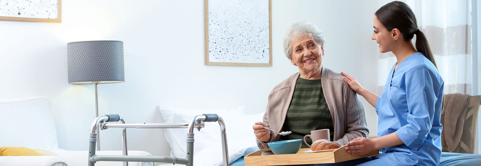 Junge Pflegerin betreut im Seniorenheim eine Seniorin beim Essen.