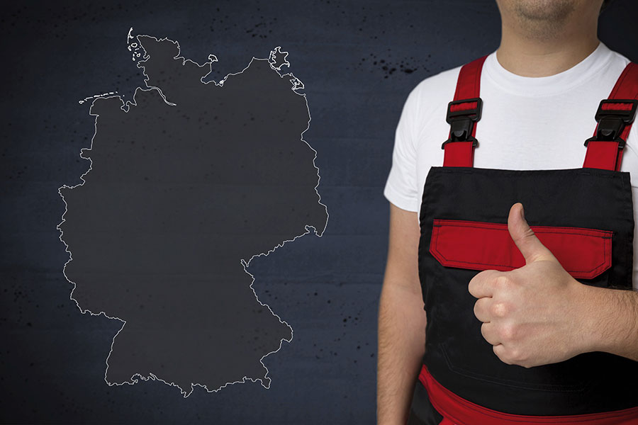Mann in Arbeitsmontur und mit gehobenem Daumen steht vor dem Umriss einer Deutschlandkarte.