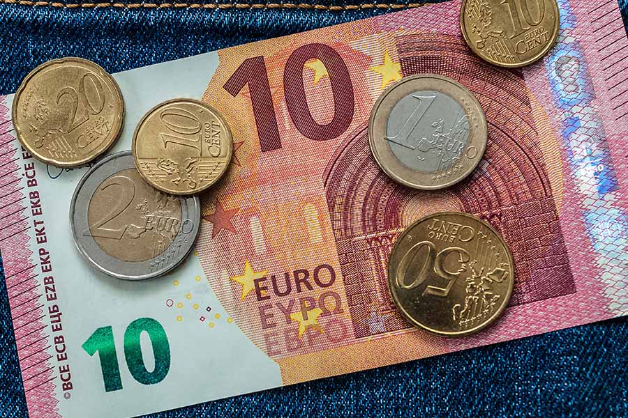 13,90 Euro, ein 10-Euro-Schein und mehrere Münzen liegen auf einer Jeanshose.