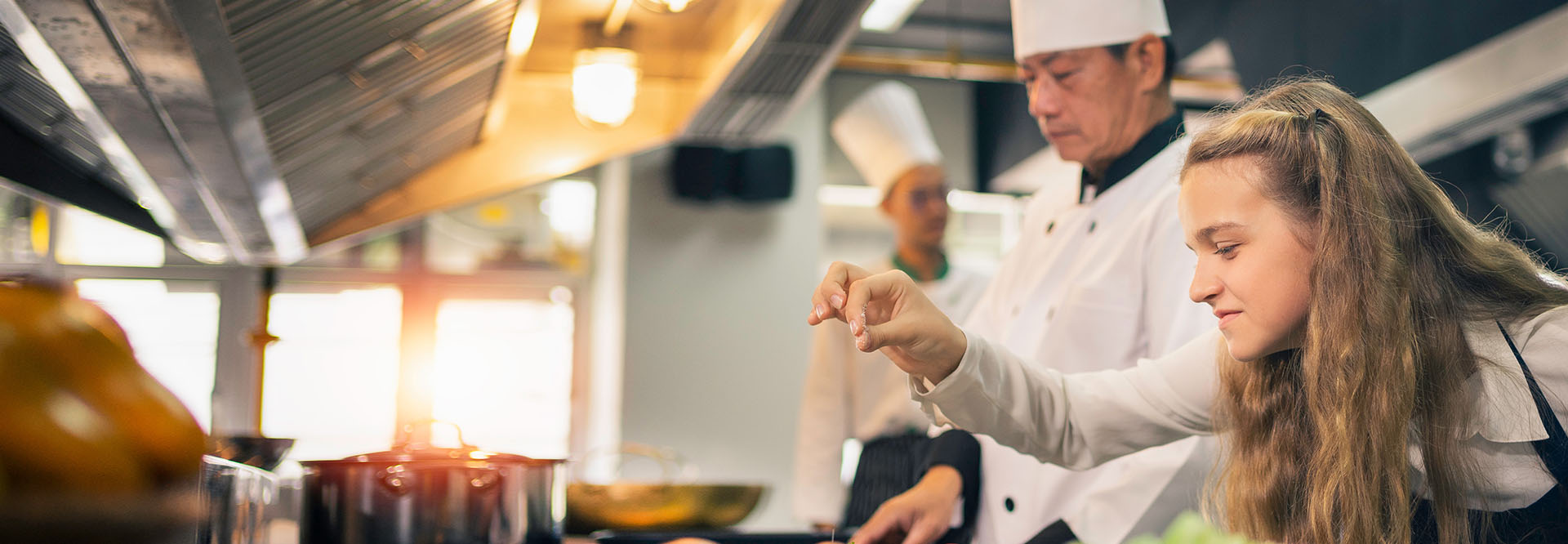 Koch und weiblicher Lehrling bei der Arbeit in einer Großküche.