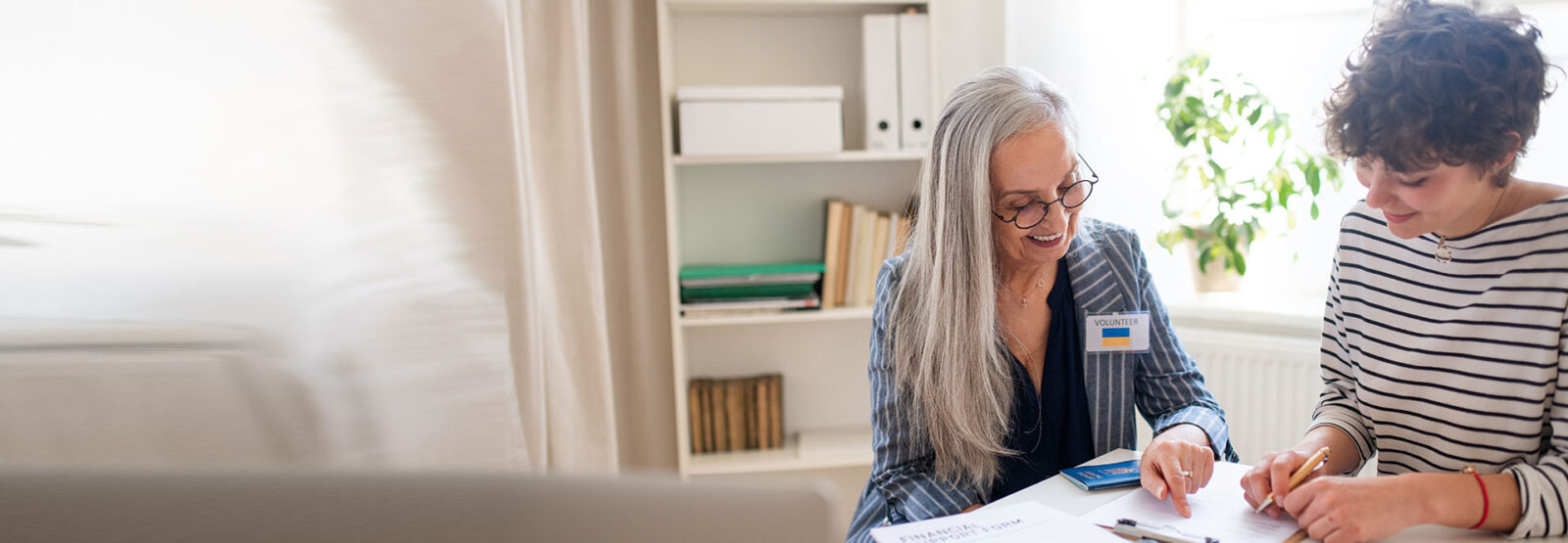Freiwillige hilft einer Ukrainerin beim Ausfüllen von Formularen