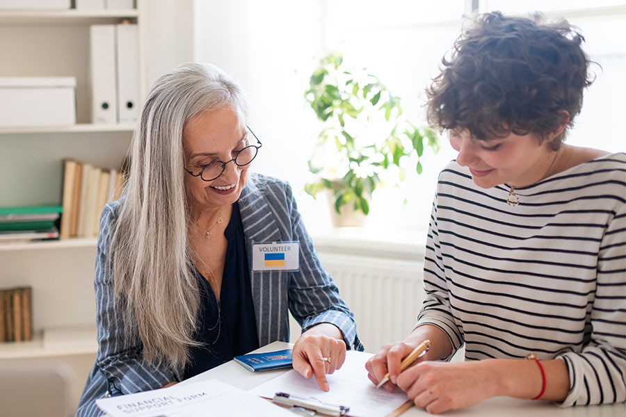Freiwillige hilft einer Ukrainerin beim Ausfüllen von Formularen