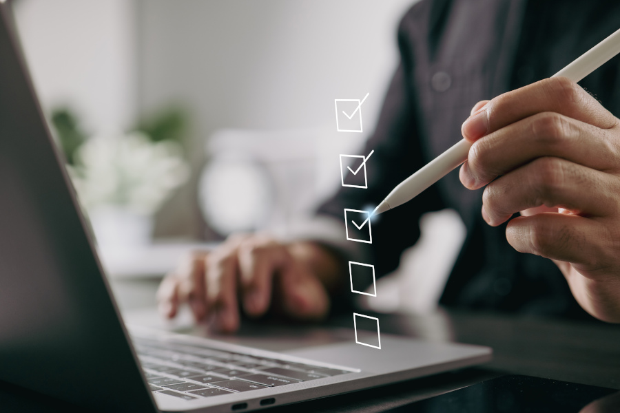 Person am Laptop hakt mit einem Stift virtuelle Kästchen