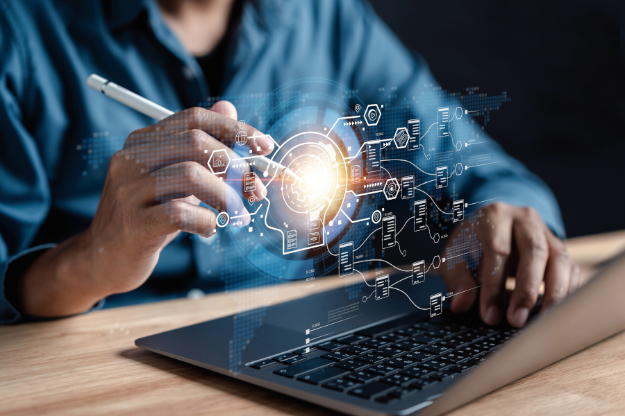 Person am Laptop aktiviert mit einem elektronischen Stift holografische Symbole über der Tastatur.