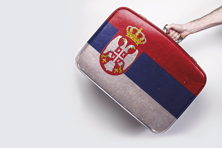 A hand is carrying a suitcase with the Serbian flag.